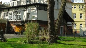 Un bâtiment traditionnel avec un toit à pignon, de grandes fenêtres et un arbre devant.