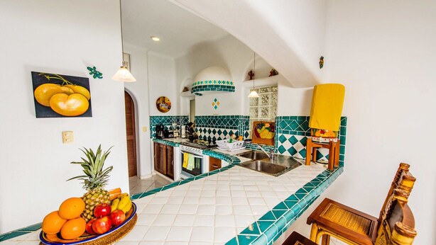 A kitchen with a tiled backsplash, a fruit bowl on the counter, and a yellow chair. - Natz Ti Ha J101 by PRP (Playa del Carmen)