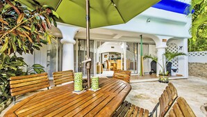 A wooden outdoor dining table with chairs, a green umbrella, and potted plants. - Natz Ti Ha J101 by PRP (Playa del Carmen)