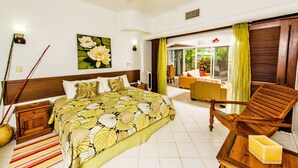 A hotel room with a bed, a wooden chair, a table with a candle, a painting of flowers, and a view of the outside. - Natz Ti Ha J101 by PRP (Playa del Carmen)