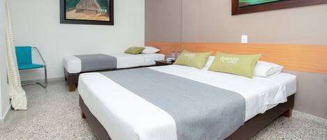 A hotel room with two beds, a chair, and artwork on the walls.