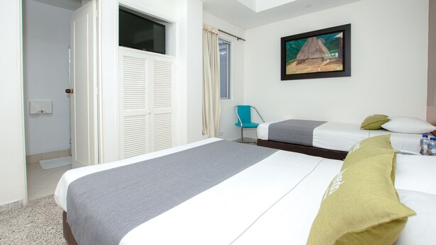 A hotel room with a large bed, a chair, a painting on the wall, and a window with curtains. - Hotel  Oasis (Rionegro)
