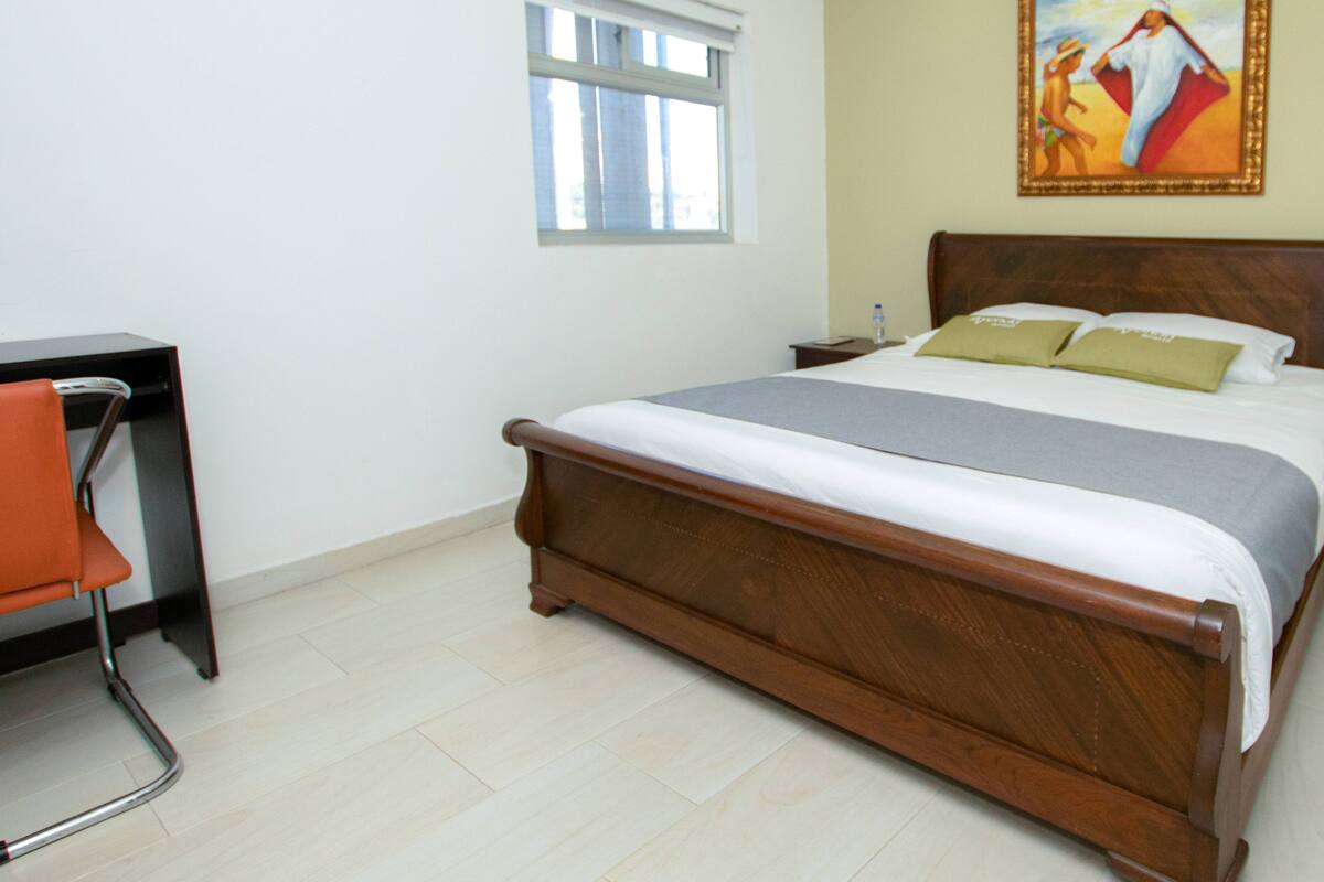 Een slaapkamer met een houten bed, een bureau en een stoel.