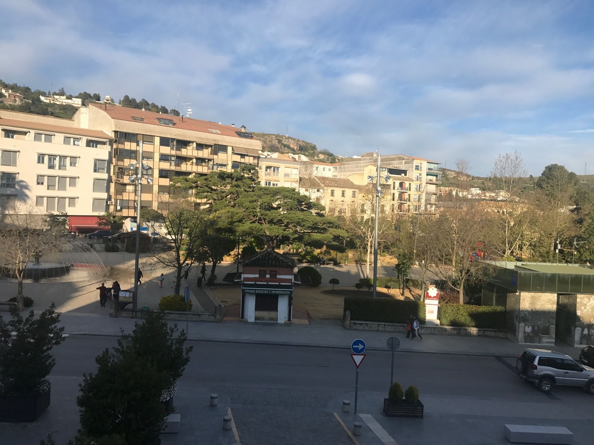 A residential area with multi-story buildings, a small park, and a street with a directional sign.