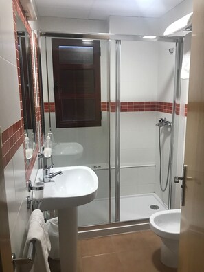 A bathroom with a glass-enclosed shower, a sink, and a toilet. - Hostal Río de Oro (Alcala la Real)