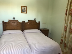A double bed with a wooden headboard, a bedside table, and a nightstand. - Hostal Río de Oro (Alcala la Real)
