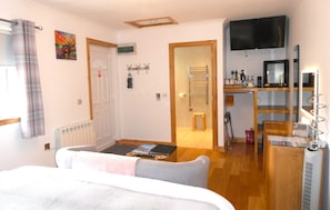 A hotel room with a bed, a desk, a TV, a radiator, and a door. - The Willows - Room Only Accommodation (Fort William)