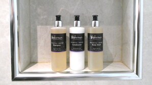 Un estante con tres productos de Wildnettle & Heather: champú, acondicionador y jabón de baño.