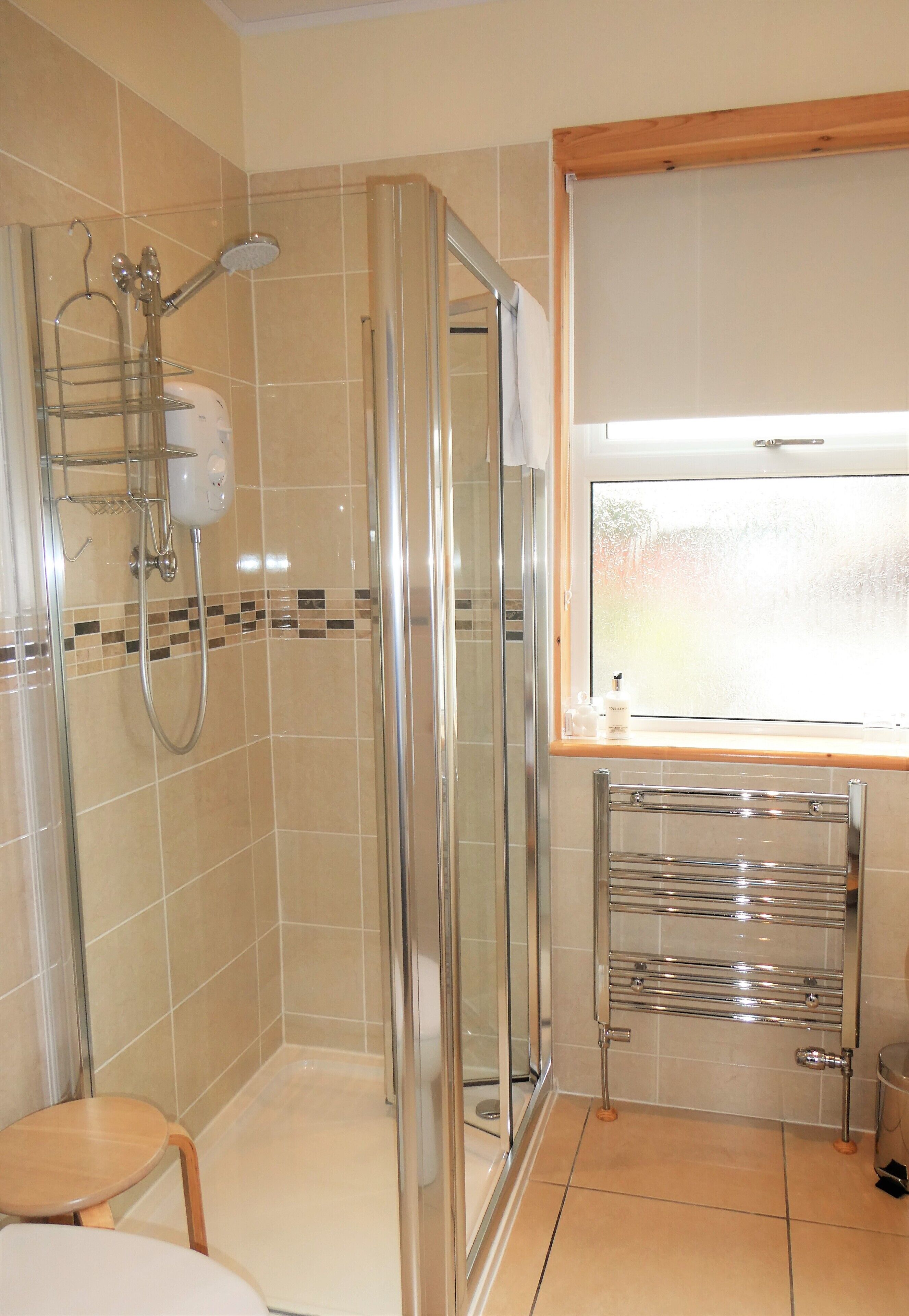 A modern bathroom with a glass shower enclosure, a vanity with a mirror, and a towel rack.