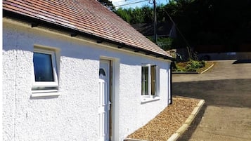A white building with a tiled roof, a door, and two windows.