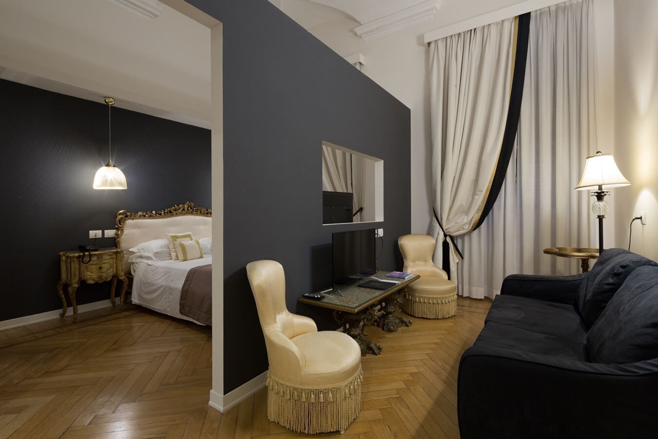 A hotel room with a bed, a desk, a chair, a sofa, and a television.