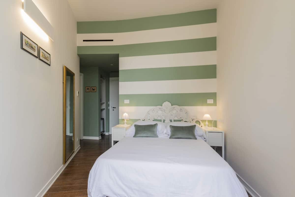 A hotel room with a bed, nightstands, and a mirror.