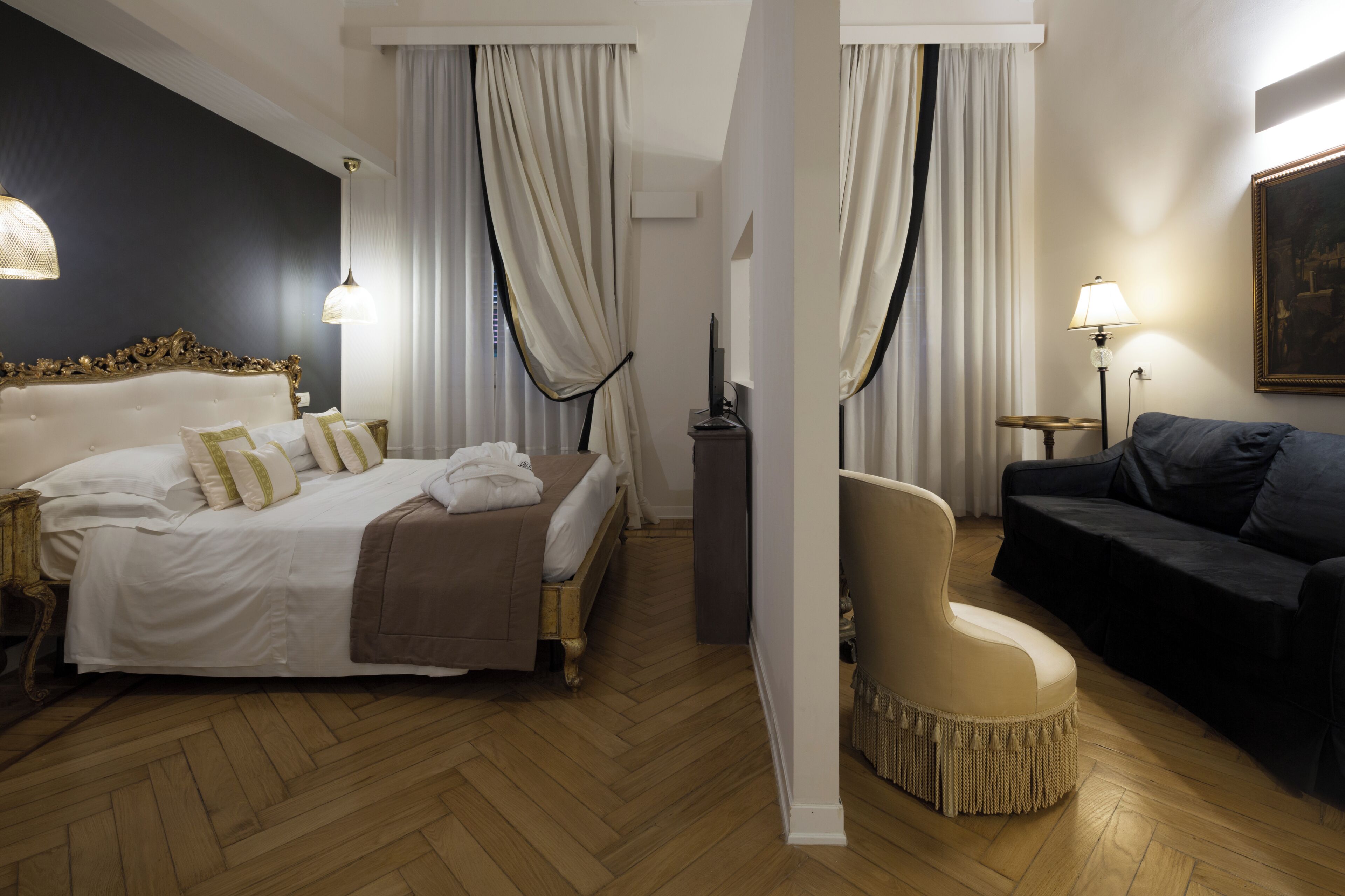 Ein Hotelzimmer mit einem großen Bett, einer Couch, einem Sessel und einem Schreibtisch mit einem Computer.