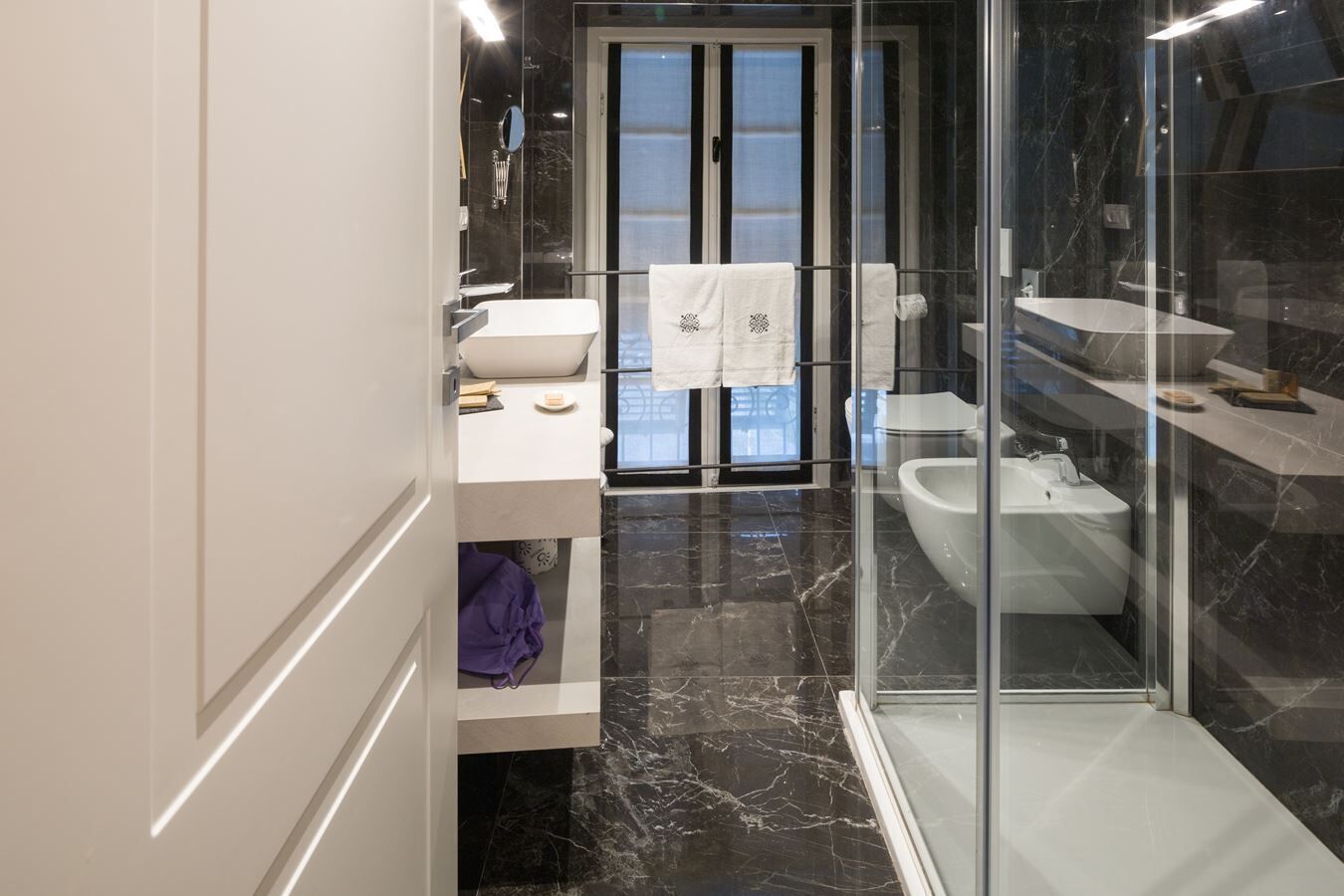 Un baño moderno con cabina de ducha de vidrio, un lavamanos blanco y un bidé.