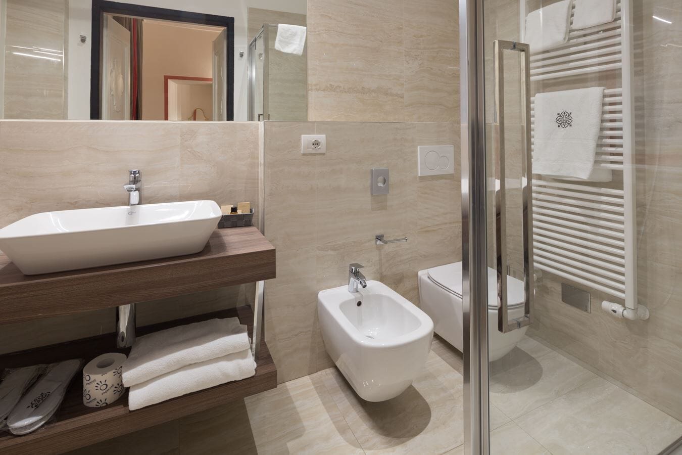 Un baño moderno con un lavamanos grande, un bidé y una cabina de ducha de vidrio.