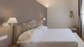 Un letto rifatto con cura, con una testiera imbottita, due lampade ai lati del letto e un piccolo comodino in legno.