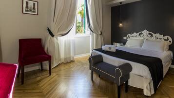 Un dormitorio con una cama, un banco, una silla roja y una ventana con cortinas.