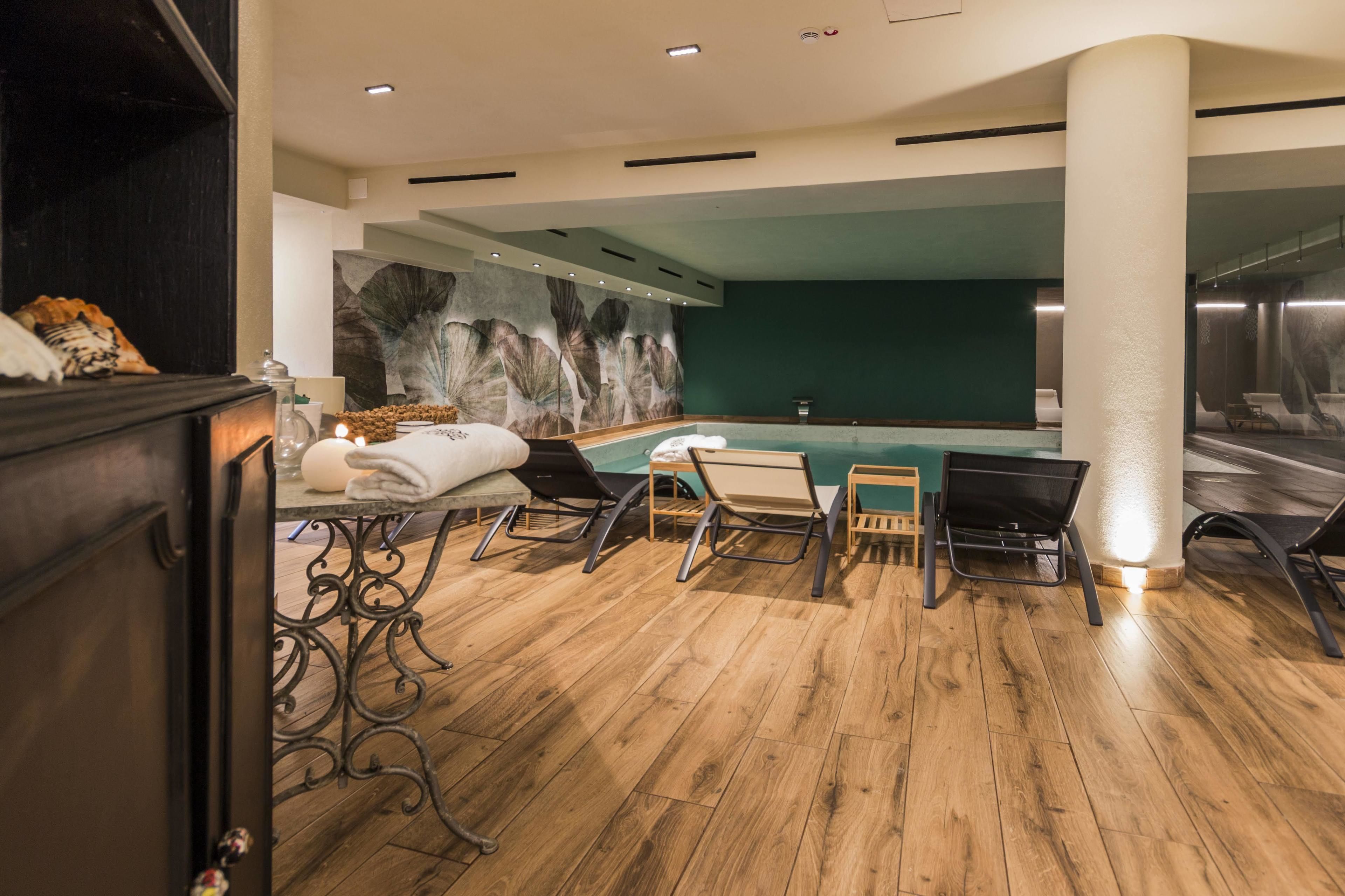 Un espace piscine intérieur moderne, doté d’un plancher en bois, d’une table de billard et de plusieurs fauteuils confortables.