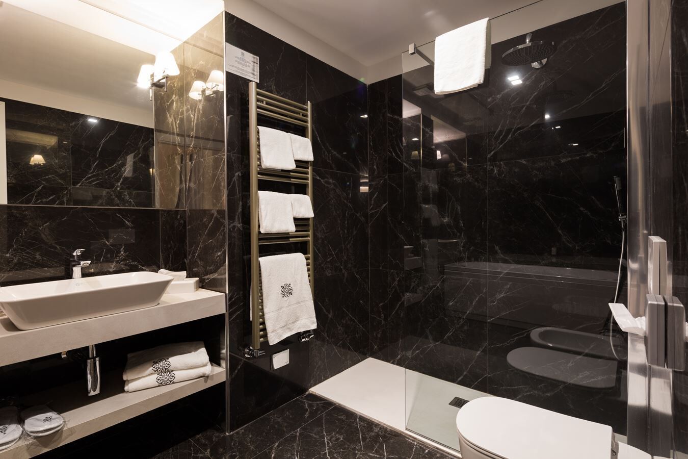 Un baño moderno con un espejo grande, un lavabo, un perchero para toallas y una zona de ducha.