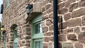 A stone building with green window frames and black fixtures. - England's Gate and Coachhouse (Hereford)