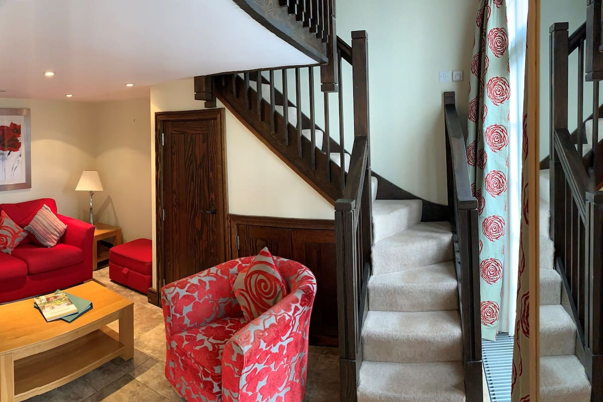 A living room with a red sofa, a coffee table, a TV, and a staircase.