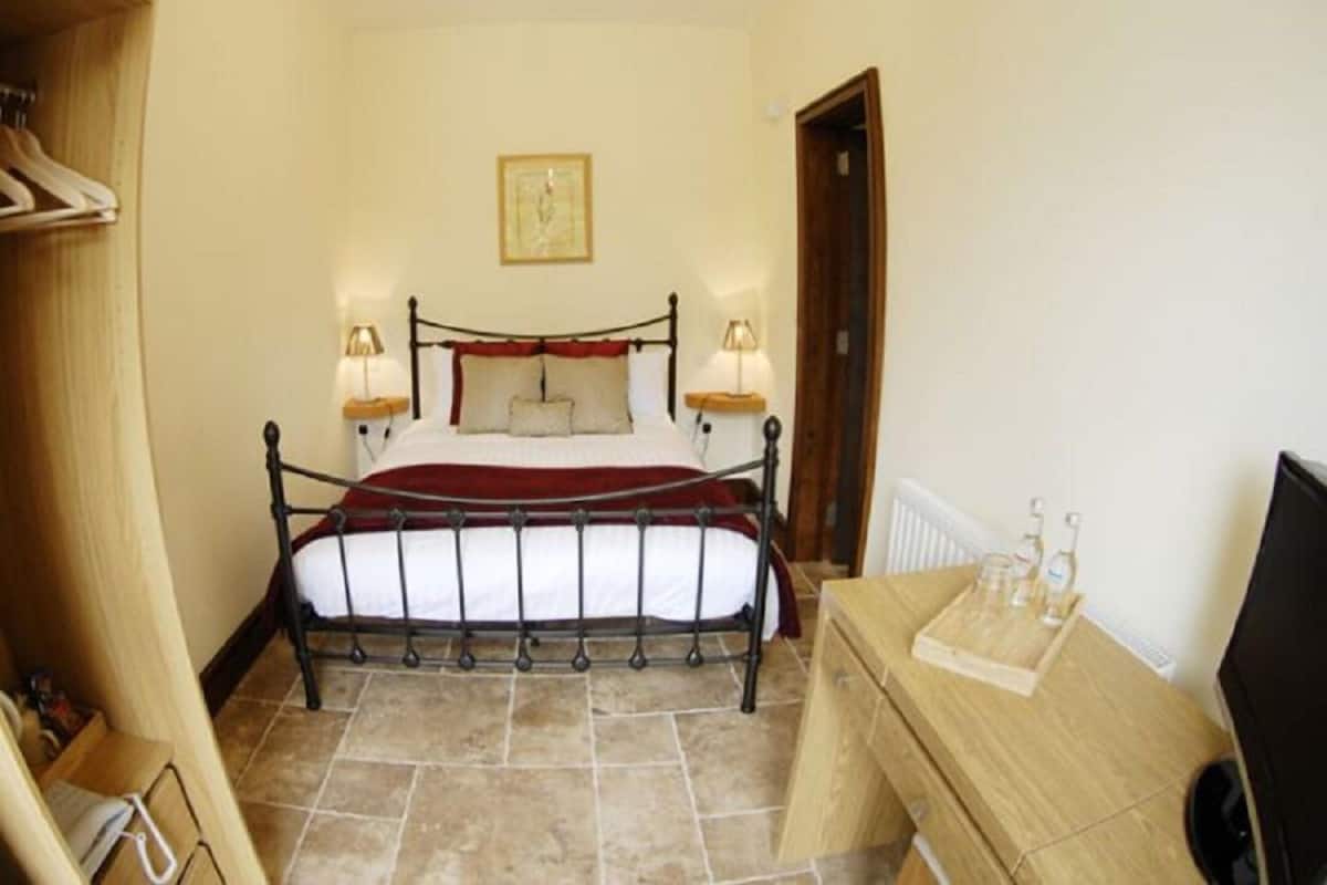 A bedroom with a bed, bedside lamps, a wooden dresser, and a radiator.