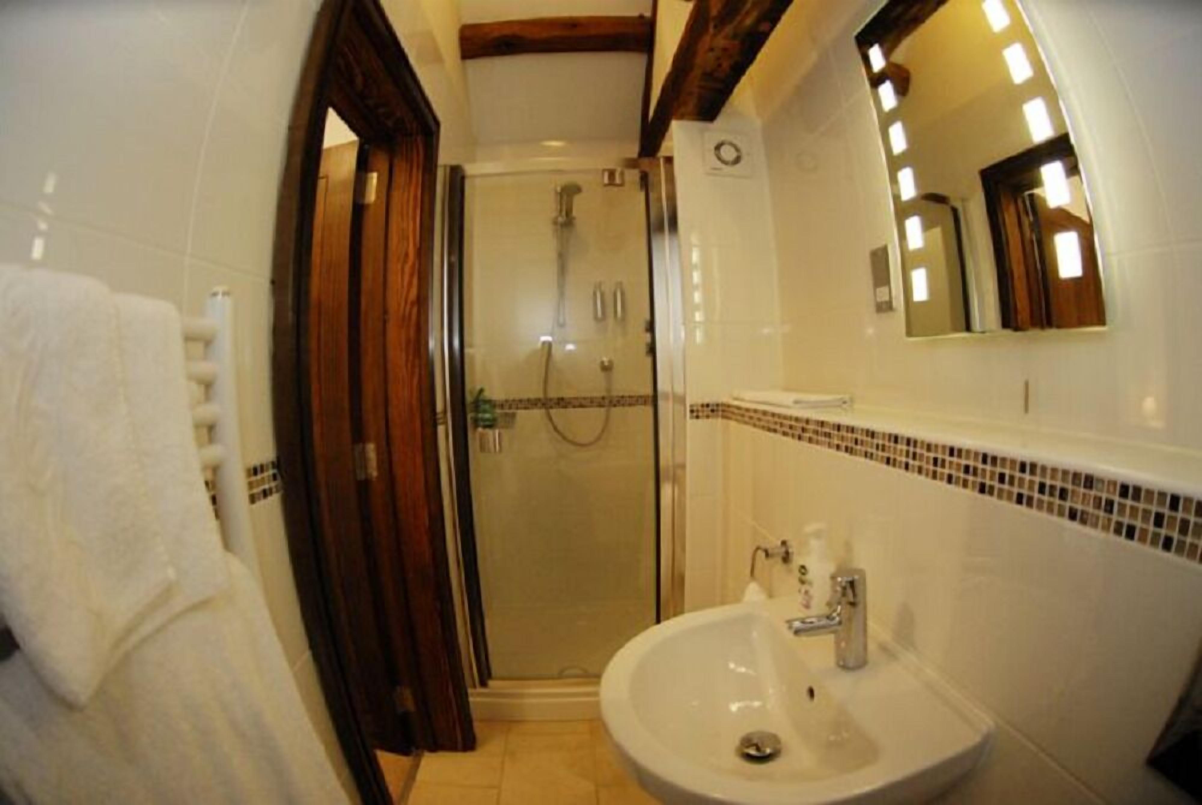 Un baño con ducha de vidrio, lavamanos y espejo.
