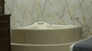 A modern bathroom with a marble wall, a built-in bathtub, and a ceiling fan. - Hotel Posada Santa Fe Sabinas (Sabinas)