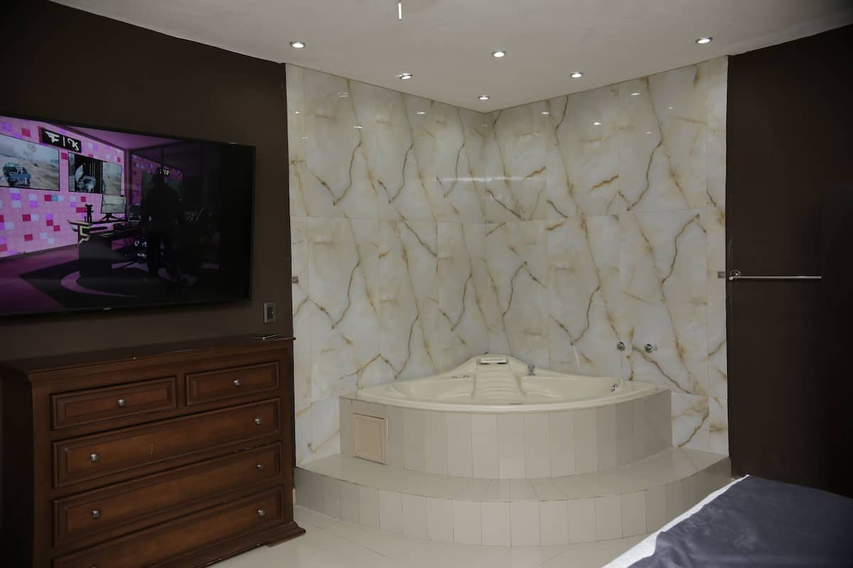 Un baño moderno con pared de mármol, una bañera grande y un aparador de madera.