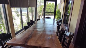 A large wooden dining table with chairs, large windows, and a view of greenery outside. - Hotel Posada Santa Fe Sabinas (Sabinas)