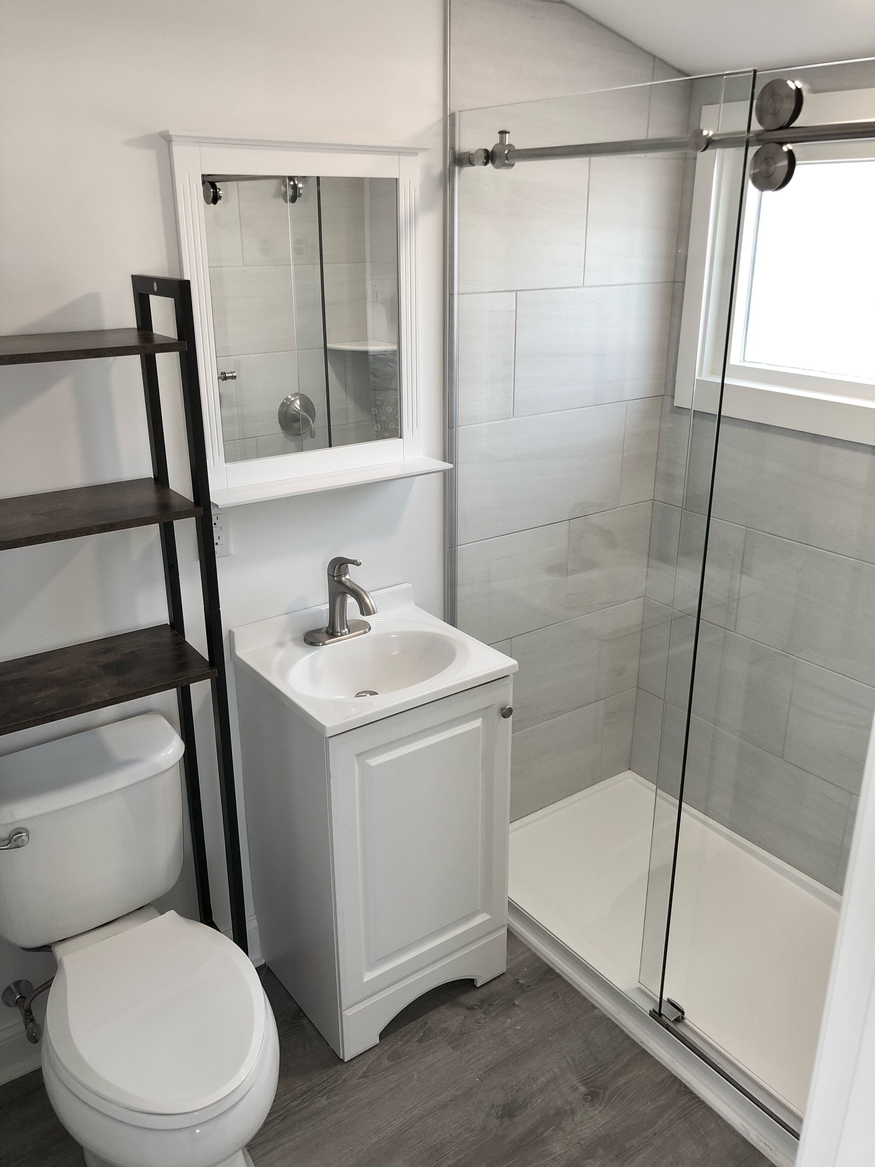 A modern bathroom with a toilet, sink, and glass shower enclosure.