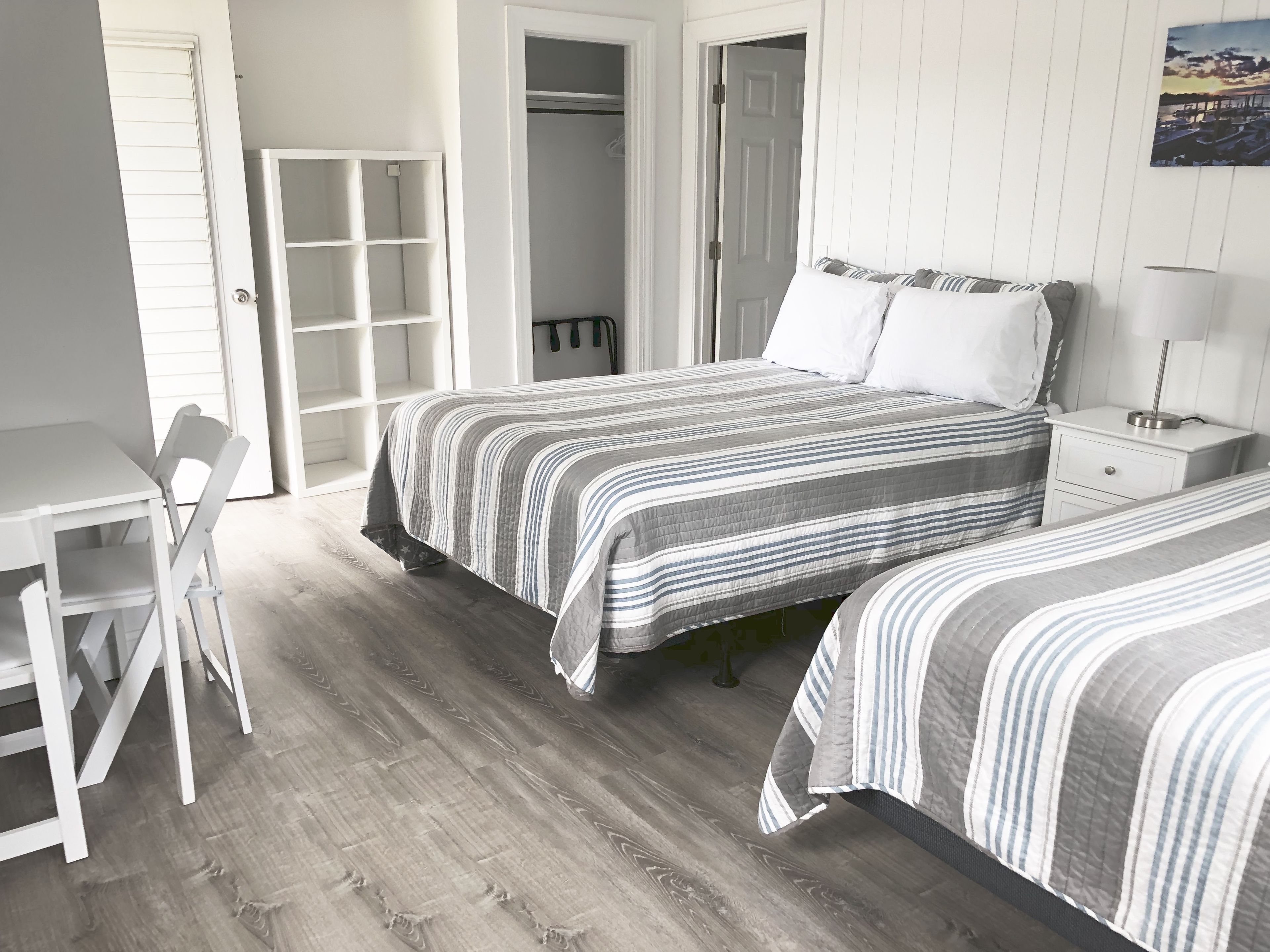 A bedroom with two beds, a desk, and a wardrobe.