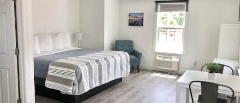 Een slaapkamer met een bed, een stoel, een tafel en een raam met uitzicht.