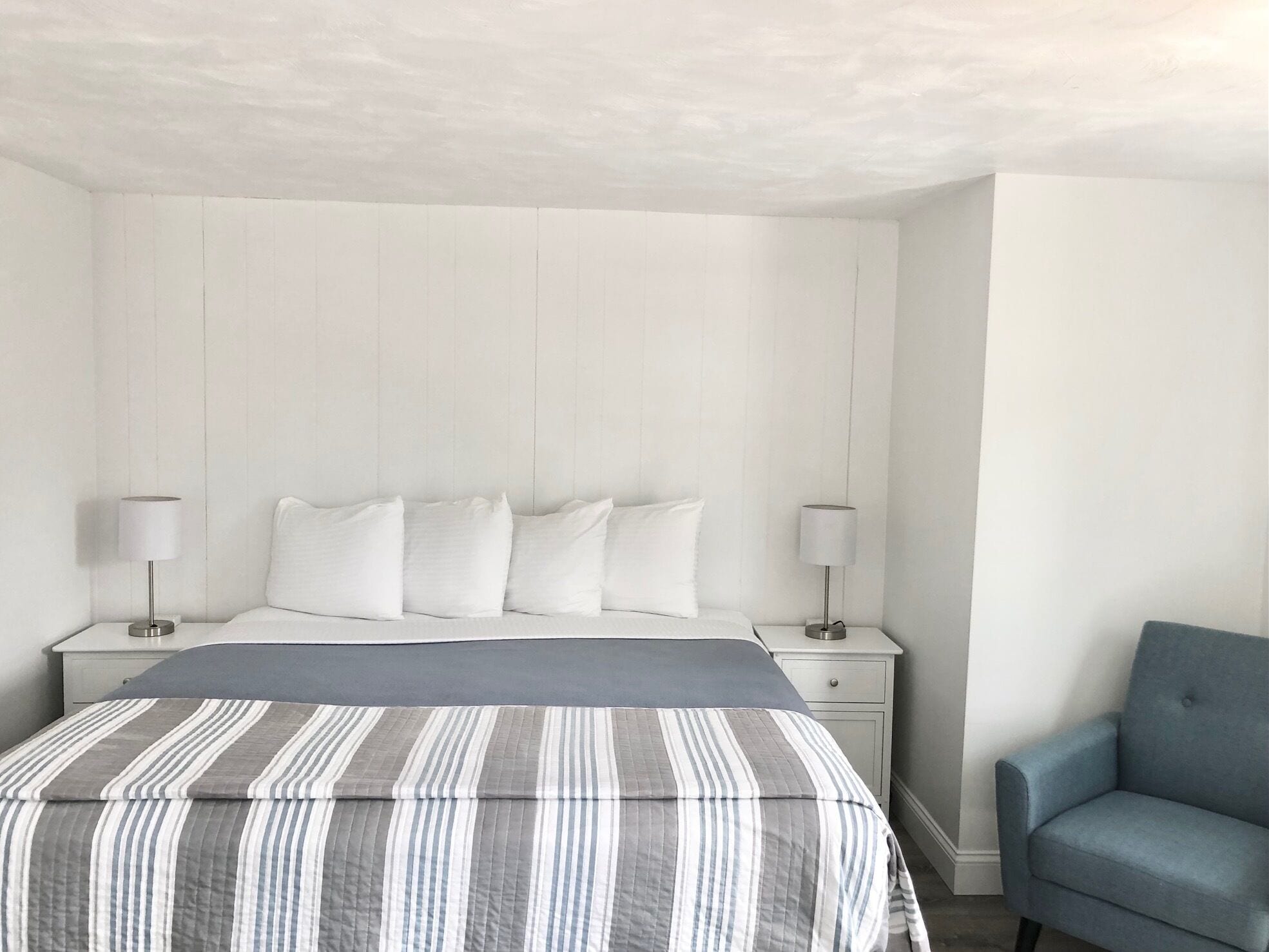 A bedroom with a bed, two bedside tables, a chair, and a headboard.