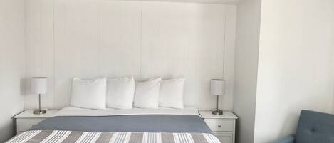 A bedroom with a bed, two bedside tables, a chair, and a headboard.