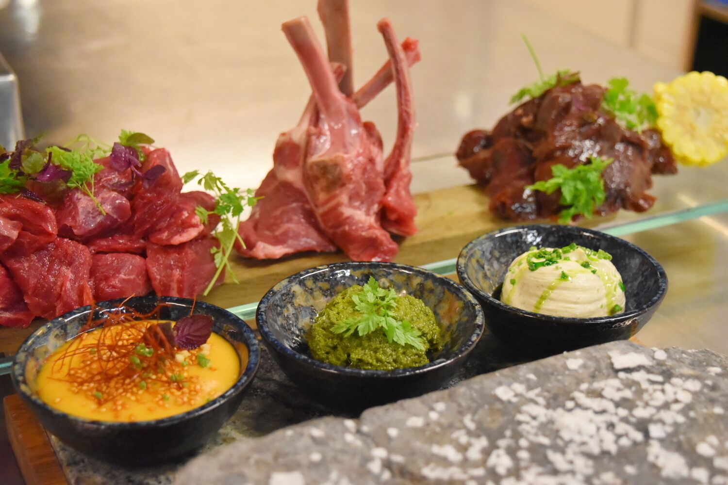 Una variedad de carnes y salsas sobre una mesa de vidrio.