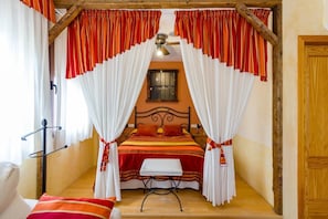 A bedroom with a bed, a bedside table, a chair, and a window. - Hotel Hospedería Zacatín (Alcala la Real)
