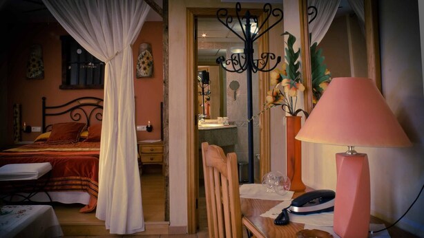 Een hotelkamer met een bed, een bureau met lamp, een stoel en een spiegel.