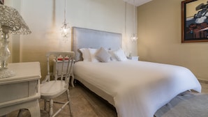 A neatly arranged bedroom with a large bed, a chair, a small table, and a chandelier. - Casa Arte Hotel Boutique by HMC - Adults Only (Cartagena)
