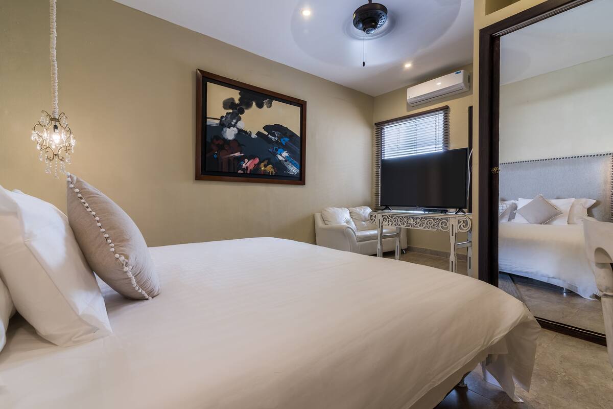 A hotel room with a large bed, a desk, a chair, and a TV.