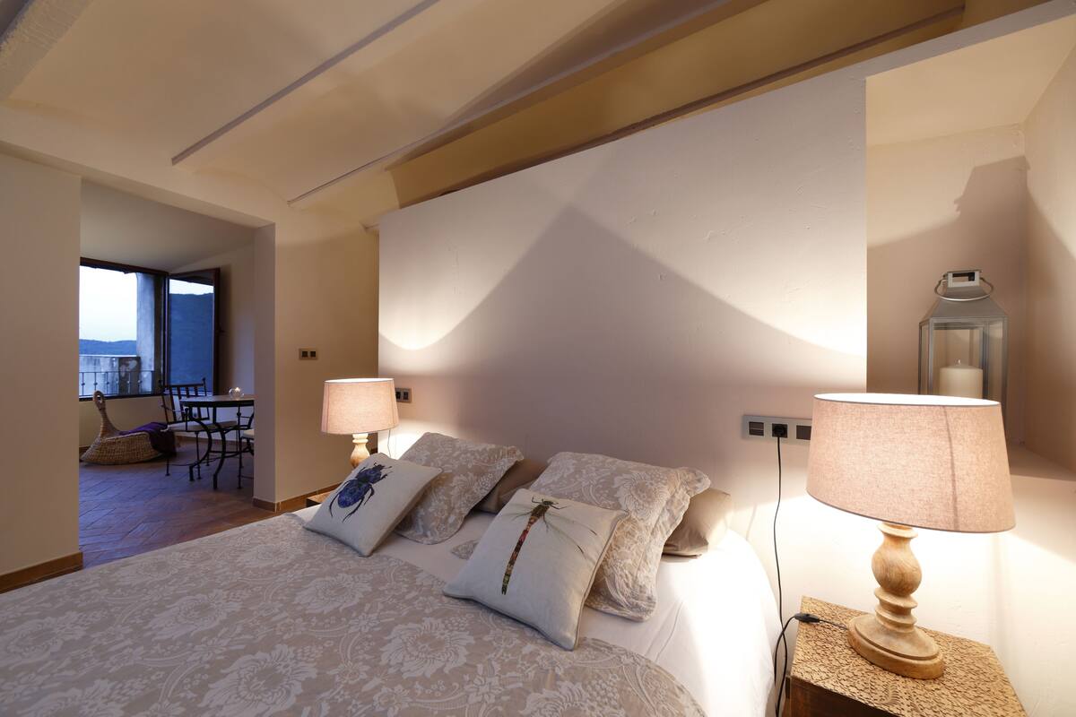 A bedroom with a bed, two bedside lamps, and a nightstand.