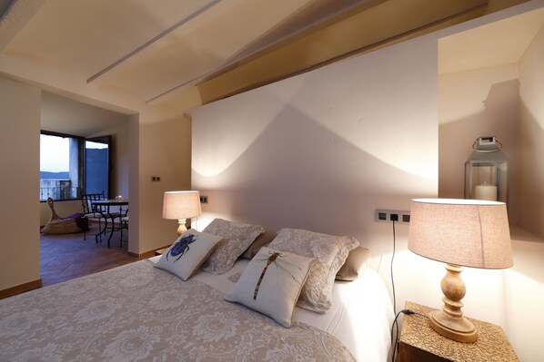 A bedroom with a bed, two bedside lamps, and a nightstand. - Dalt Vila (Eslida)