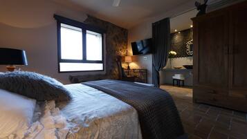 Een slaapkamer met een bed, een televisie, een kledingkast en een stenen muur.