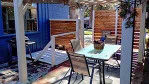A covered patio area with a table and chairs, a pergola, and a blue wall.