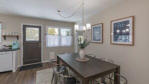 A dining area with a wooden table, chairs, a vase with flowers, and wall art.