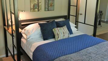 A bunk bed room with a blue quilted bedspread, pillows, and a blanket. There are wall art pieces and a lamp on the bunk bed.