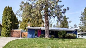 A single-story house with a blue exterior, a red door, and a chimney.