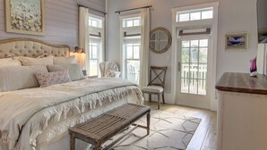 Un dormitorio con una cama grande, un banco de madera, una silla y vistas al exterior a través de una ventana.