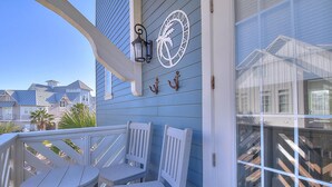 A blue house with a porch, two white chairs, and a small table.
