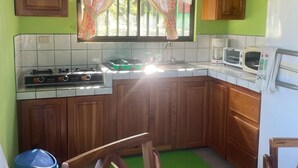 Eine Küche mit Holzausstattung, einem Gasherd, einer Mikrowelle und einem Fenster mit Vorhängen.